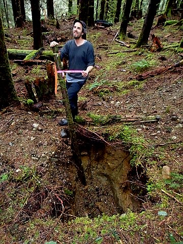 A volunteer stands over a septic field test hole near the trail