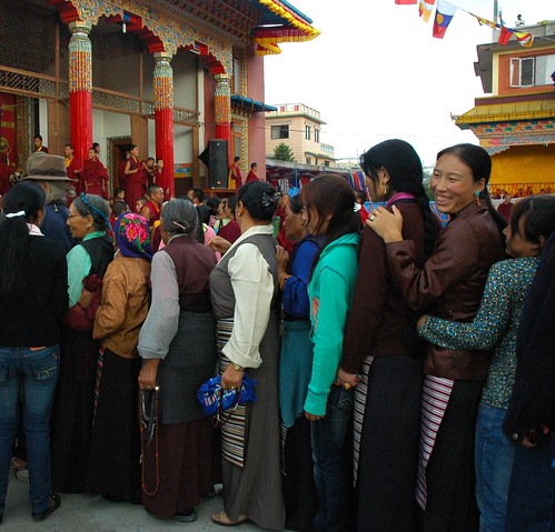 Smiling Tibetan women queueing tightly into line for long life initiation, mala, chubas traditional striped aprons, Tharlam Monastery courtyard, Tibetan Buddhist, Boudha, Kathmandu, Nepal by Wonderlane