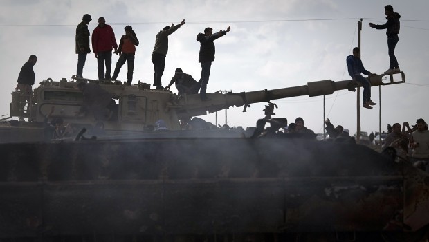 Libyan people celebrate on a knocked out Gadaffi tank