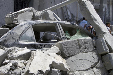 In this photo taken on a tour, a damaged car lies underneath rubble opposite a damaged residential building in Tripoli, Libya, Sunday, June 19, 2011. The US and Europe are justifying the carnage. by Pan-African News Wire File Photos