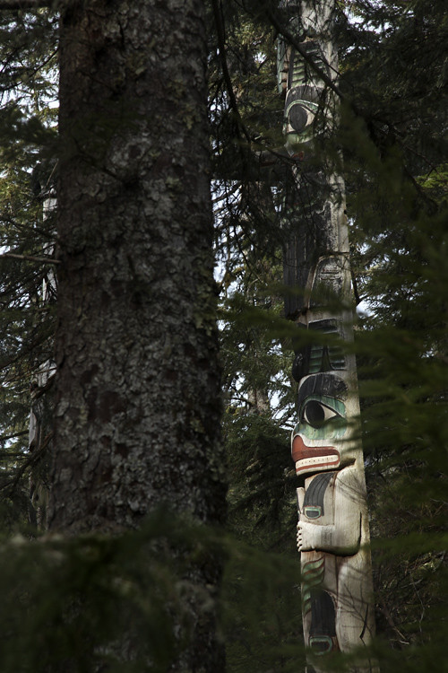 figures of the Spencer Pole, seen through trees, Totems Historic District, Kasaan, Alaska
