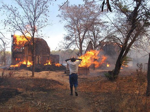 A worker on the Campbell farm watches helplessly as farm buildings burn.