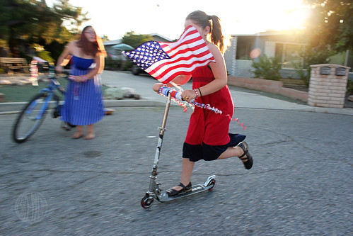 Girl riding a scooter with American flag and streamers 