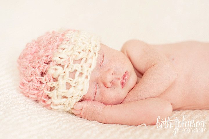 newborn baby girl in pink and white hat