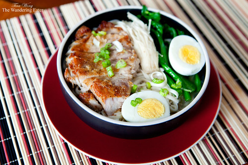 Bowl of noodles with seared pork chop, enoki mushrooms, choy sum tips, and hard boiled egg