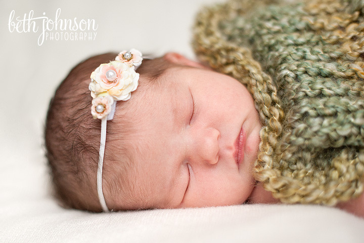 baby girl in green cocoon with white headband