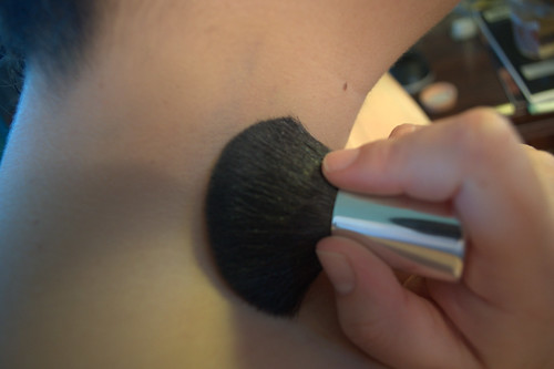 lightly brushing the power over the concealer, using a circular motion
