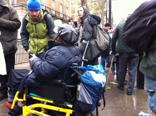 People milling around with a wheelchair user in focus in the foreground