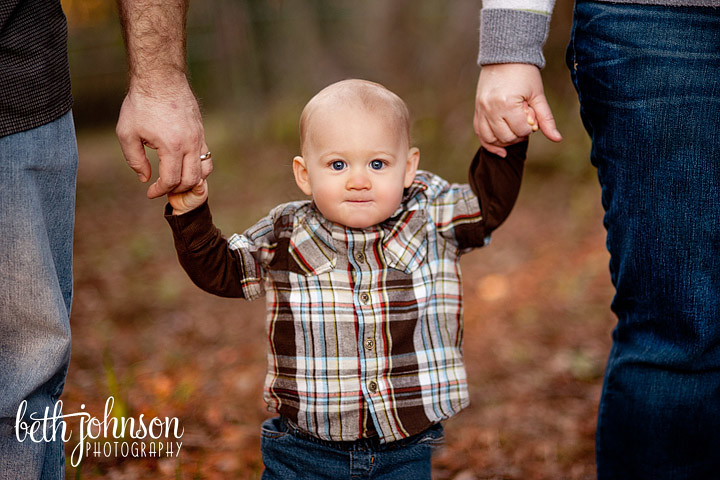 little boy on his first birthday with his parents holding his hands