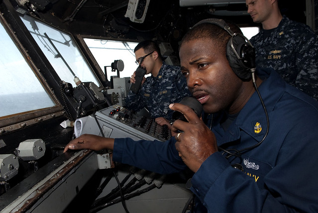 USS Whidbey Island Sailor communicates on radio. by Official U.S. Navy Imagery