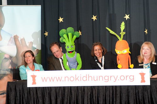 Left to right on stage, School Board Vice Chairperson Abby Raphael, Arlington County School Superintendent Patrick K. Murphy, Federation of Virginia Food Banks Executive Director Leslie Van Horn, Barcroft Elementary School Principal Miriam Hughey-Guy, as two of the Super Sprowtz super-powerful vegetable super hero puppet characters, Brian Broccoli and Colby Carrot, encourage the students, parents and teachers of Barcroft Elementary School to get up and dance, during the launch of the Virginia No Kid Hungry Campaign at the Arlington, VA, school on Tuesday, June 7, 2011. USDA Photo by Lance Cheung.
