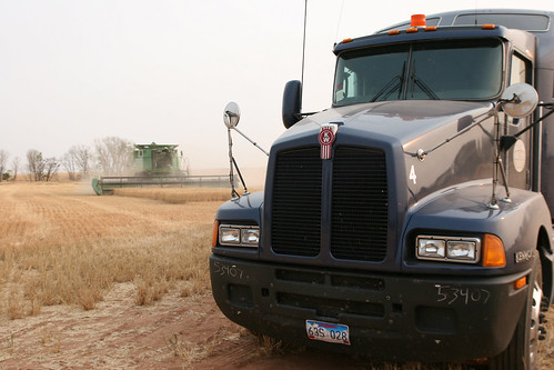 One of our trucks parked at the end of the field with a combine in the background.