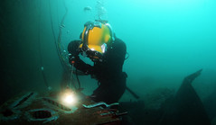 Navy Diver 2nd Class Ryan Arnold welds a patch onto an underwater structure.