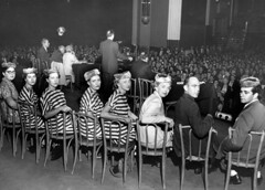 Women dressed in prison uniforms sitting on st...