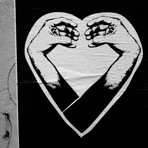 sticker graffiti of arms crossed at the elbows, hands turned back toward each other, creating the shape of a heart