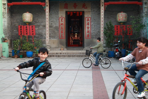 kids cycling in front of a temple in Macau