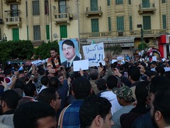Protesters in Tahrir Square, one with a poster...