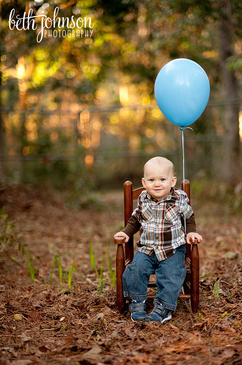 one year old boy with blue balloon in chair