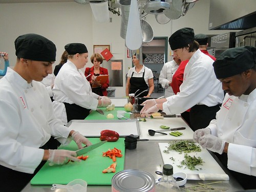 High school Culinary Arts students and Amy Lee, Culinary Arts Instructor and Recipe Team member, utilize their knife skills to chop vegetables during the recipe demonstration for the judging team.