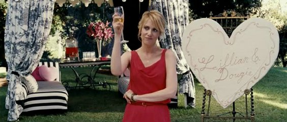 Kristin Wiig, wearing a red dress, makes a toast