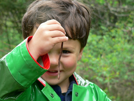 Young boy examining an earthworm. 