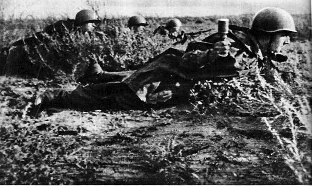 Soldado russo em ação. Arrastando-se sobre o barro, estes soldados soviéticos se aproximam de uma posição alema. Levam granadas nas mãos.