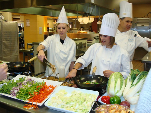 Smithson Valley High School culinary arts students Rachel Roff, left, and Emily Richardson, right, learn new cooking techniques from Chef Ralph Garcia.