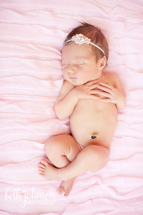 newborn baby girl on pink ruffled blanket