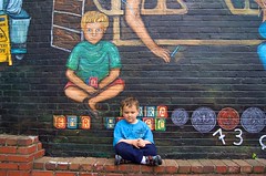 Regina Places her son next to his image in the mural 2