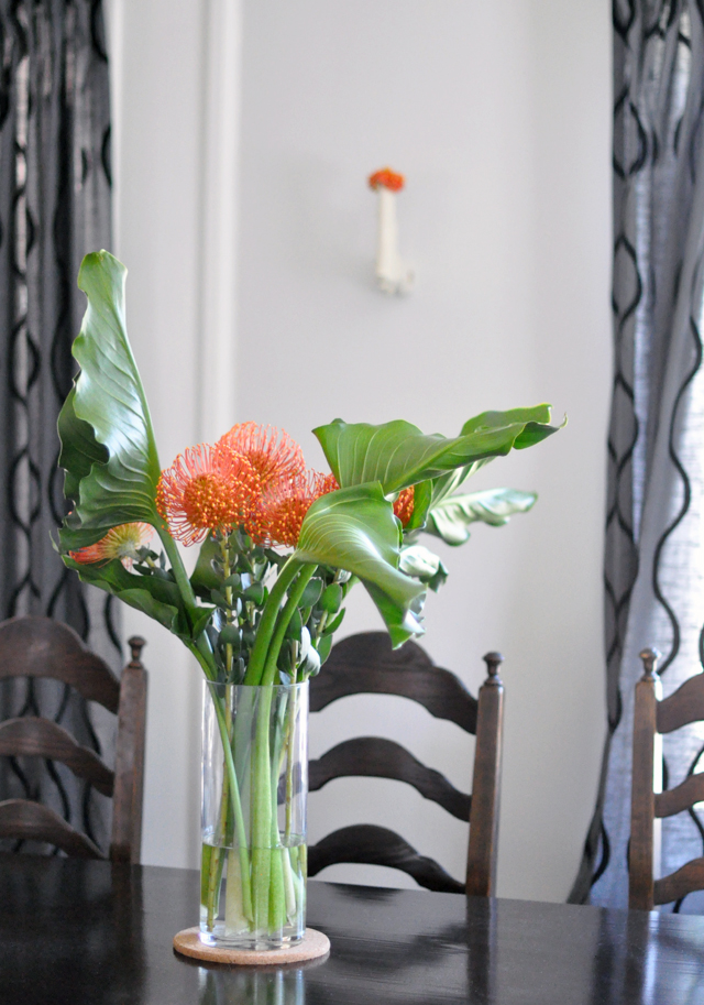 dining room table + orange flowers + gun vase