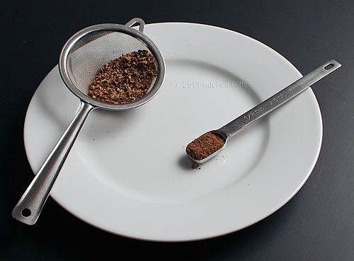 Roasted Sichuan Peppercorns, Ground Powder in measuring spoon, husks in a strainer