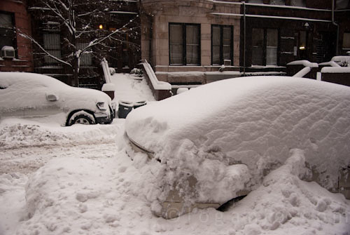 Car buried under snow in NYC with a subway sign