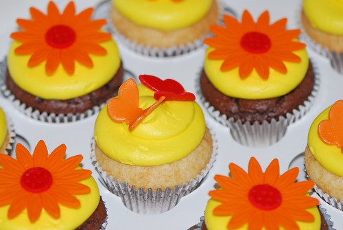 yellow orange and red cupcakes topped with butterflies and daisies