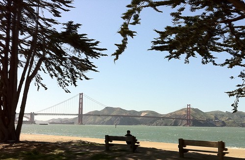 man on bench facing Golden Gate