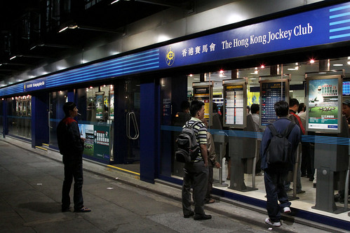 Smokers looking through the window of a Hong Kong Jockey Club store