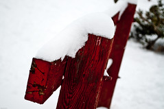 close up of a bright red wooden fence with bright white snow on top