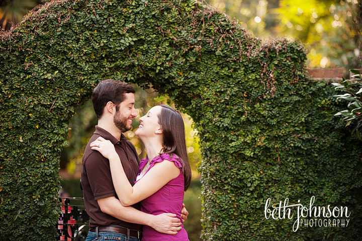 engaged couple in front of ivy covered arch