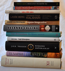 a stack of books including works by VS Naipaul, Suzanne Collins, and JRR Tolkien