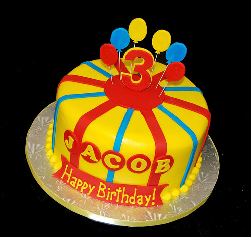Brightly colored birthday 3rd cake for a Curious George themed party