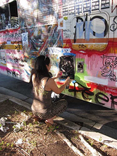Sugar Junkies. Girl spraying stencil on van.  (Photograph courtesy by Pawn Works)
