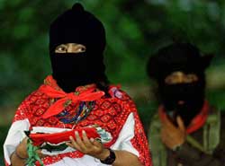 Comandante Ramona wears a black face mask and a white shirt with a red scarf. Only her eyes are visible