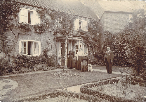 Family and dog in their garden at home. 1900s