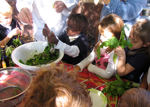 A child gives one last toss to the salad before sampling.