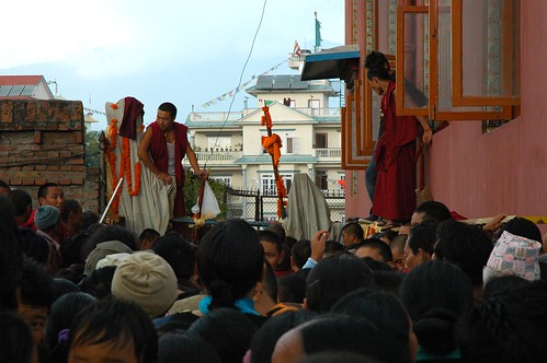 Monks oversee the crush at the gate routing people behind Tharlam Monastery to the stage, marigold flowers, Boudha, Kathmandu, Nepal by Wonderlane