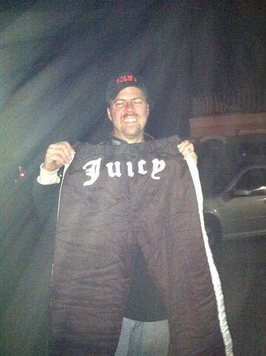 Brian holds his gift- racing pants with the word 'Juicy' stitched over the bottom