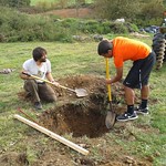 Two students working together to dig a hole.