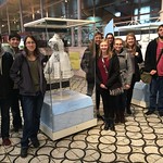 Students and professor pose around a dress displayed in a museum