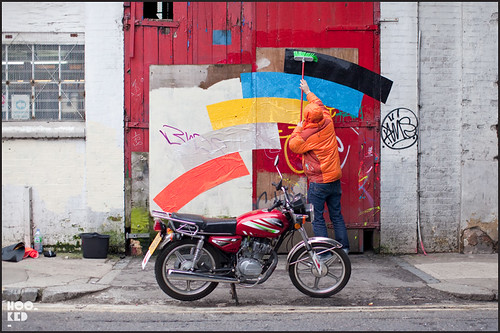 Artist Momo at work installing colourful street art installation in London