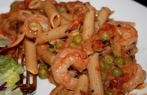 plate of ziti pasta covered in shrimp, peas, and red sauce