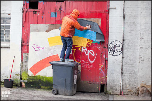 Artist Momo at work installing colourful street art installation in London